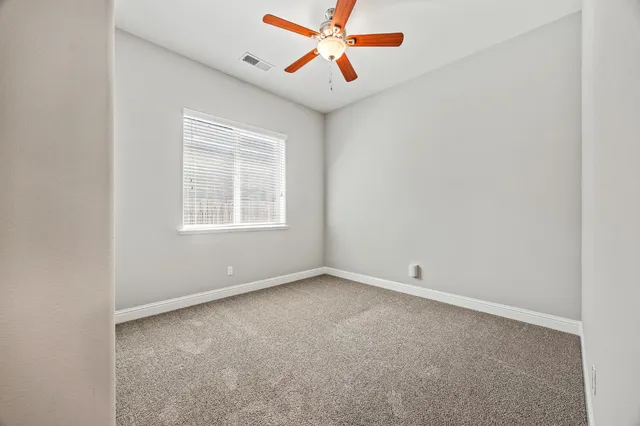an empty room with windows and fan