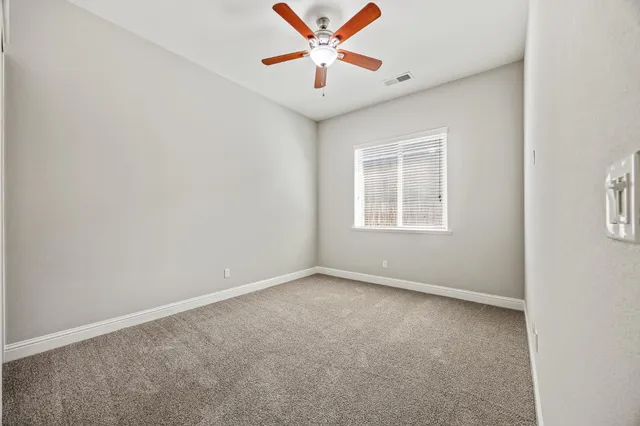 an empty room with a window and a ceiling fan