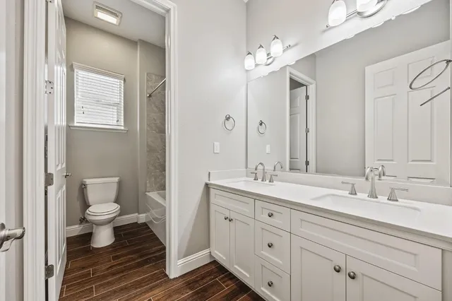 a bathroom with a double vanity sink a toilet and a mirror