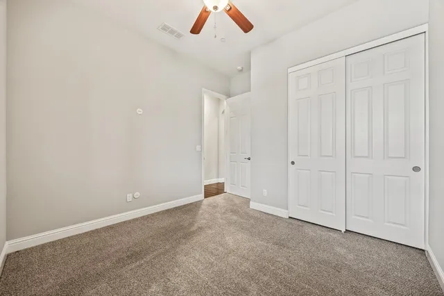 an empty room with a ceiling fan and window