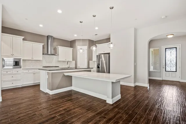 a kitchen with stainless steel appliances a refrigerator a stove top oven and white walls