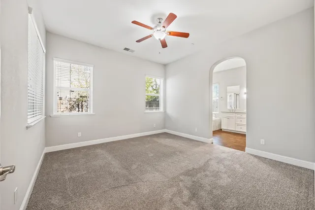 an empty room with windows and ceiling fan