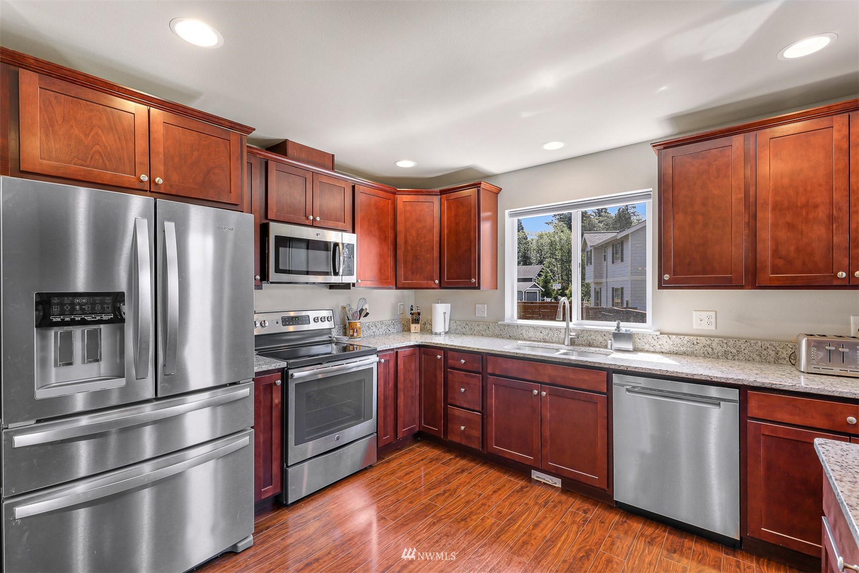 4601 Hall Road Blaine, WA 98230 - Photo 19 of 39 a kitchen with stainless steel appliances granite countertop wooden cabinets a sink a stove a refrigerator with grey cabinets and wooden floor