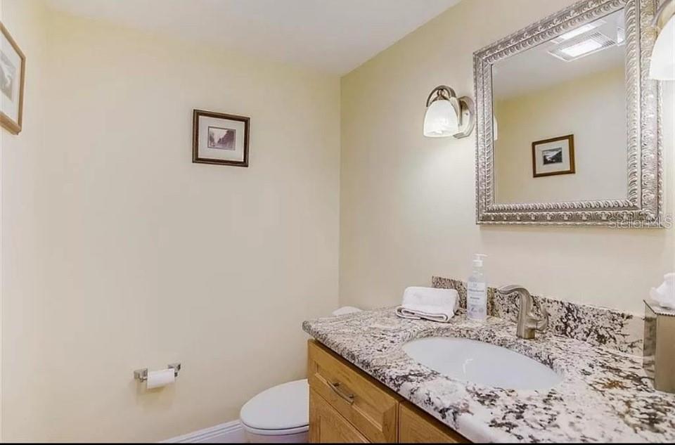5911 Midnight Pass Road, Unit 601 Sarasota, FL 34242 - Photo 14 of 48 a bathroom with a granite countertop sink mirror vanity and toilet