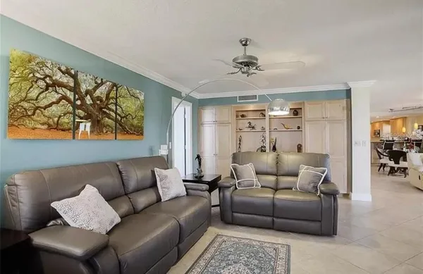 a living room with furniture a ceiling fan and a flat screen tv