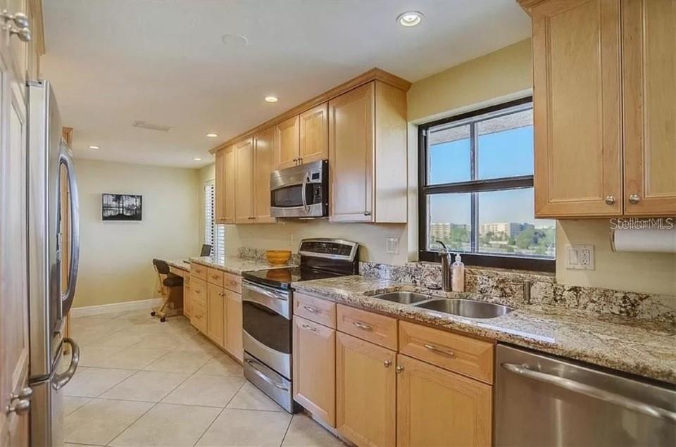 5911 Midnight Pass Road, Unit 601 Sarasota, FL 34242 - Photo 10 of 48 a kitchen with stainless steel appliances granite countertop white cabinets a sink a stove a microwave and a refrigerator