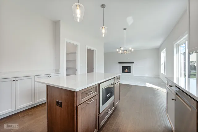 a view of a kitchen with a sink and dishwasher a stove top oven with wooden floor