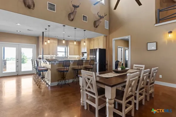 a kitchen with stainless steel appliances kitchen island granite countertop a table chairs and a refrigerator
