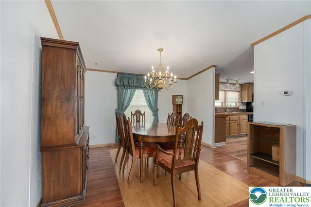 a dining room with wooden floor a chandelier a wooden table and chairs