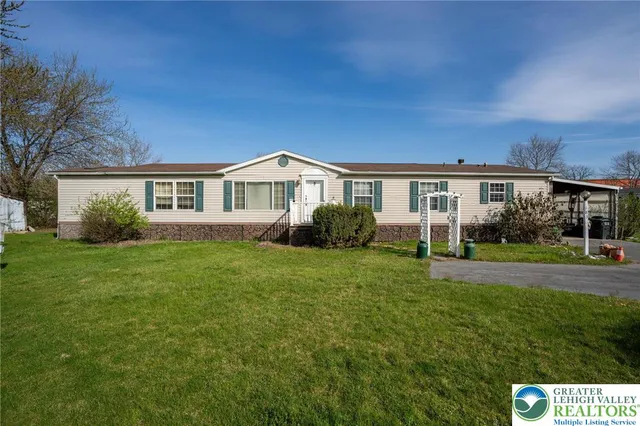 a view of house in front of a big yard with large trees