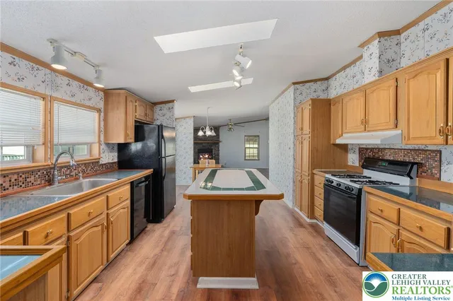 a kitchen with stainless steel appliances kitchen island granite countertop a refrigerator and a sink