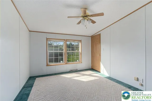 an empty room with windows and fan