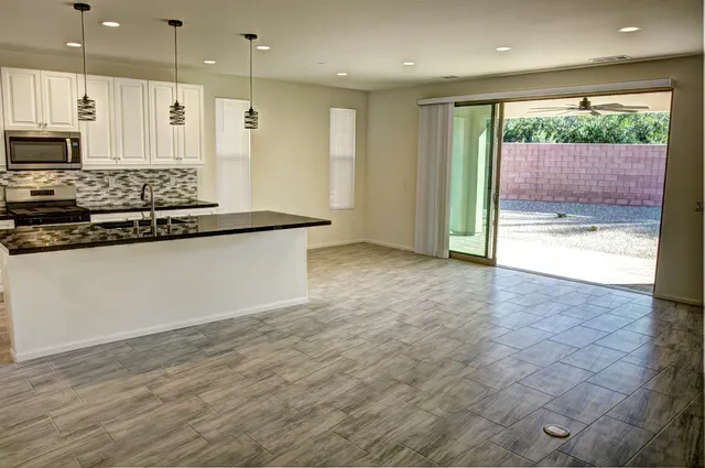 a large kitchen with stainless steel appliances kitchen island granite countertop a large counter top and a wooden floors