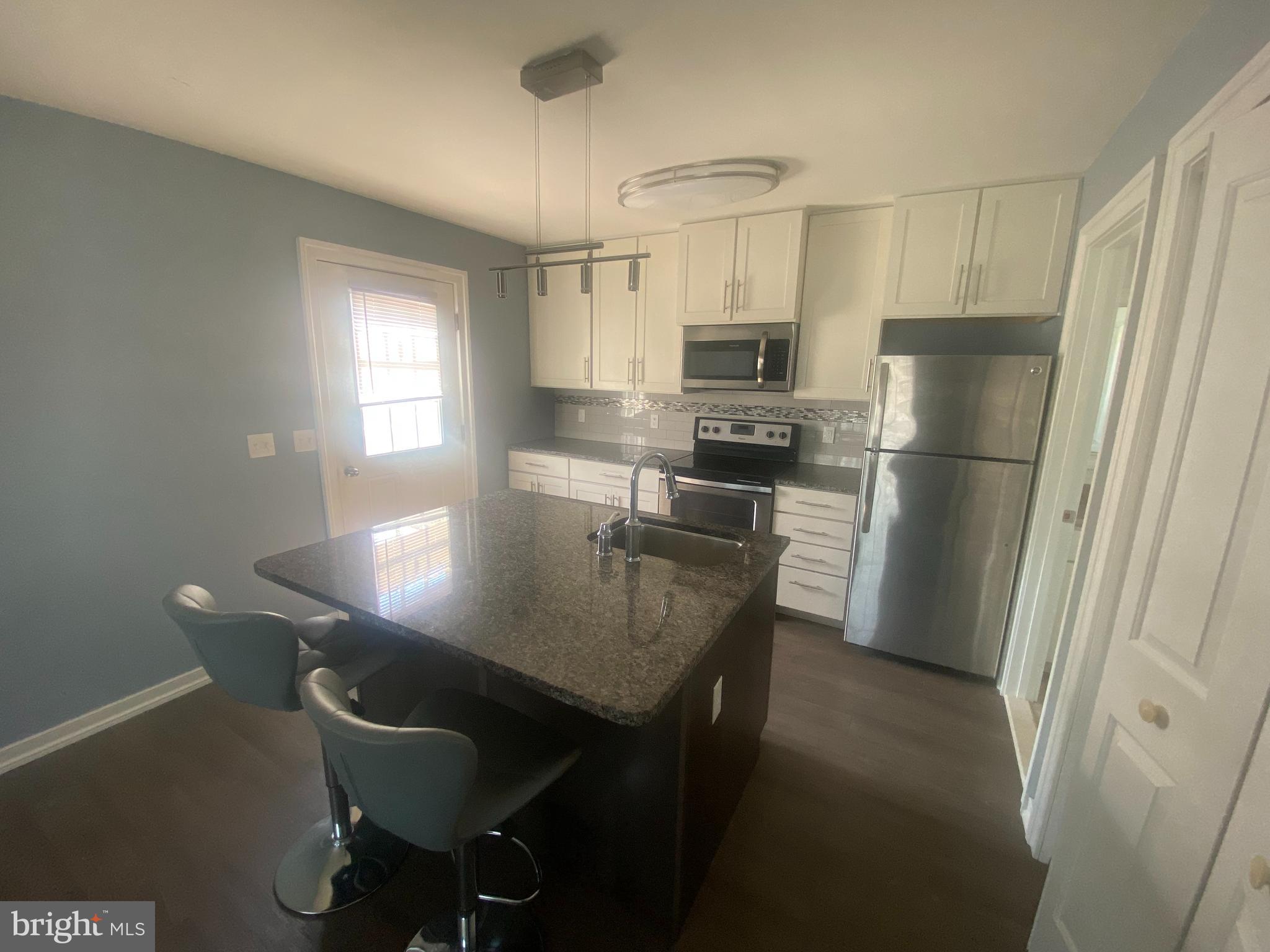 a kitchen with refrigerator a sink and chairs