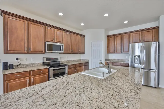 a large kitchen with kitchen island a large counter top a sink and a stove