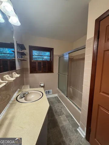 a bathroom with a granite countertop sink a mirror and a shower