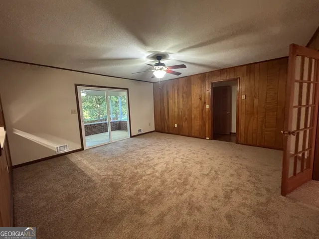 an empty room with windows and fan