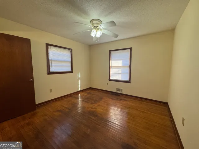 a view of an empty room with a window and wooden floor