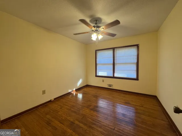 a view of an empty room with wooden floor and a window