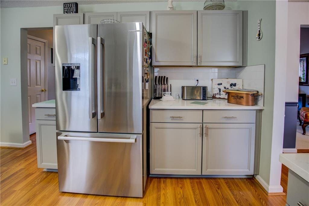 4885 Hidden Creek Place Decatur, GA 30035 - Photo 13 of 52 a kitchen with wooden floor white cabinets and stainless steel appliances