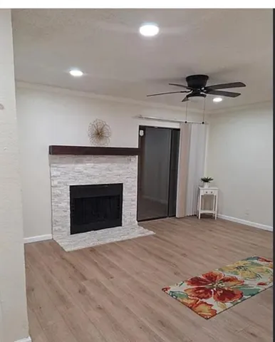 a view of an empty room with a fireplace and a chandelier fan