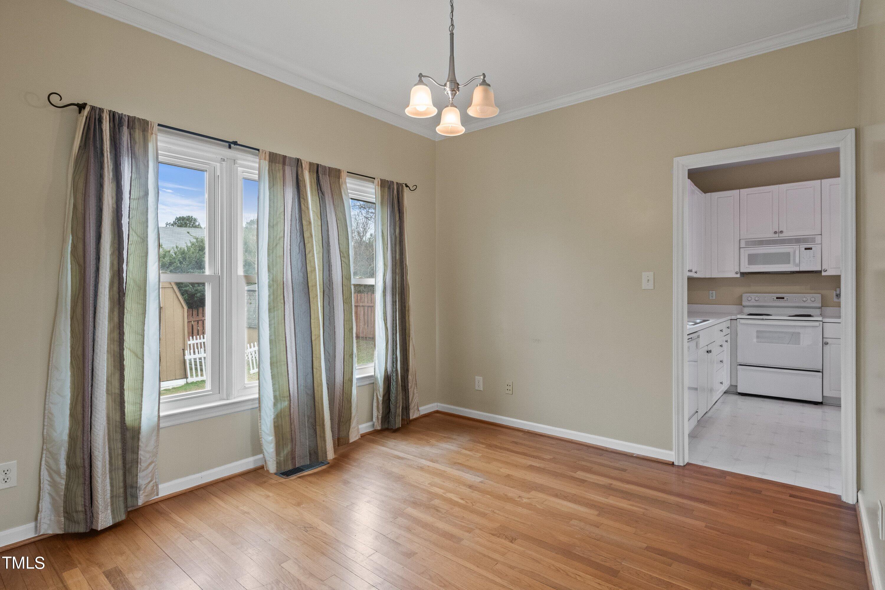 9421 Dawnshire Road Raleigh, NC 27615 - Photo 8 of 32 an empty room with wooden floor cabinet and windows