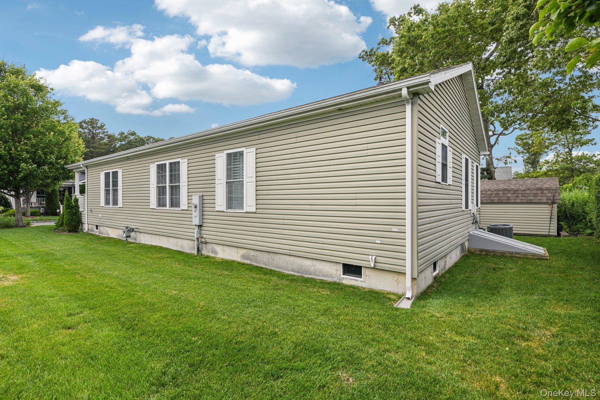1661 Old Country Road, Unit 543 Riverhead, NY 11901 - Photo 20 of 26 View of property exterior with a lawn and a central AC unit