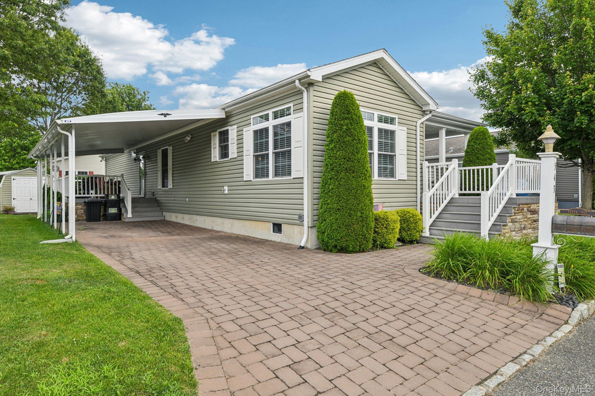 1661 Old Country Road, Unit 543 Riverhead, NY 11901 - Photo 2 of 26 View of property exterior with a carport, a lawn, driveway, crawl space, and a storage shed