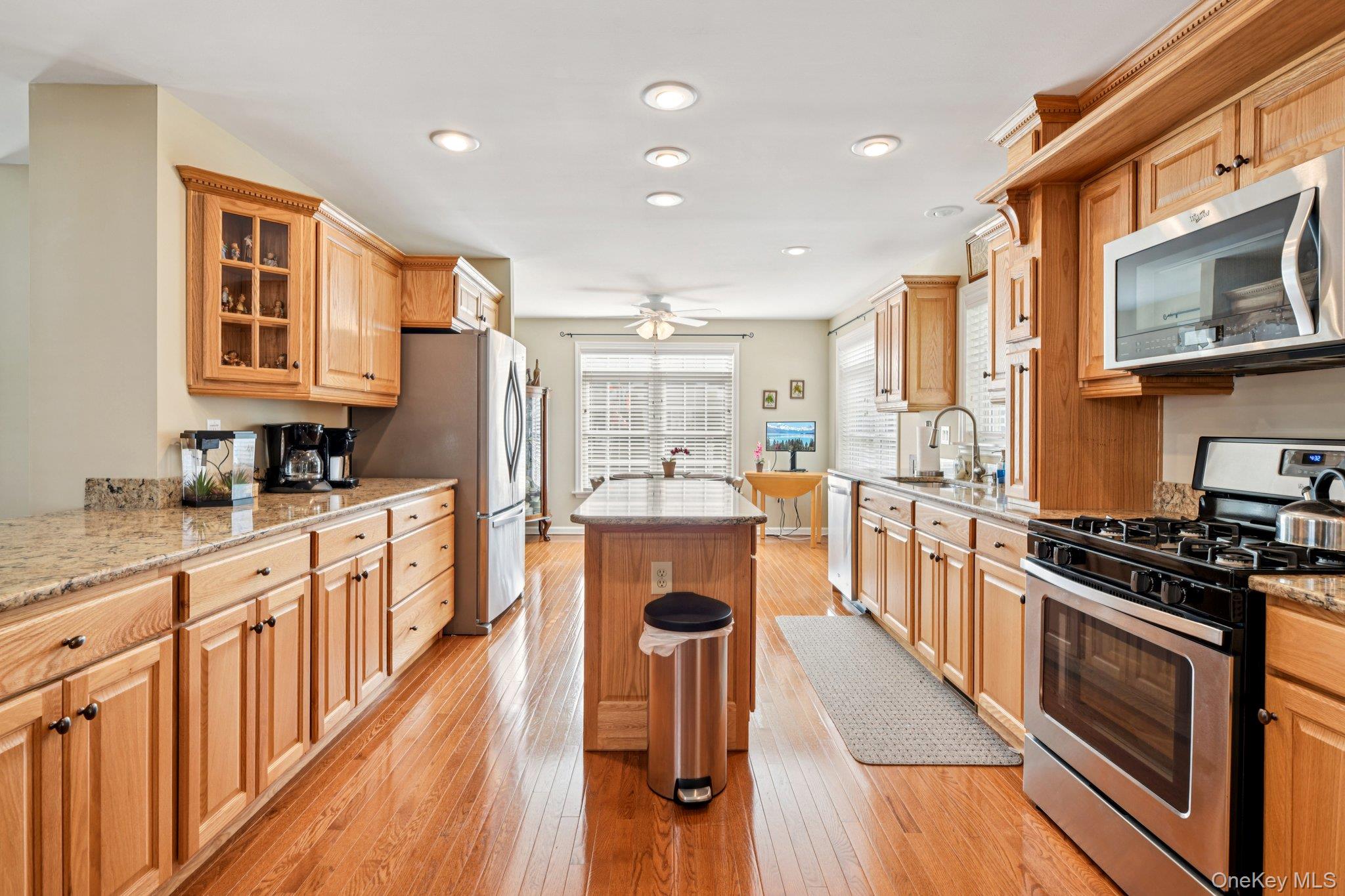 1661 Old Country Road, Unit 543 Riverhead, NY 11901 - Photo 8 of 26 Kitchen featuring stainless steel appliances, a kitchen island, a ceiling fan, light stone countertops, and glass insert cabinets