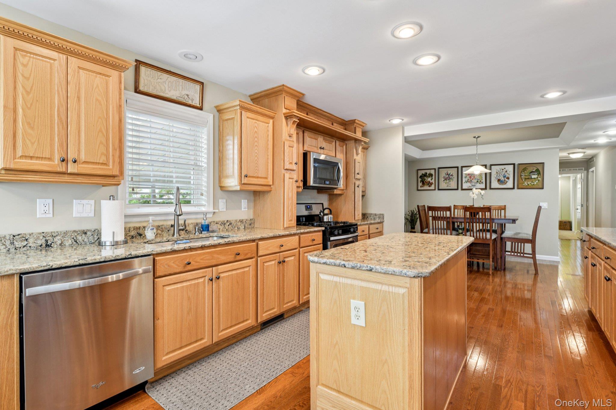 1661 Old Country Road, Unit 543 Riverhead, NY 11901 - Photo 9 of 26 Kitchen with stainless steel appliances, a center island, light brown cabinetry, light wood-type flooring, and light stone countertops
