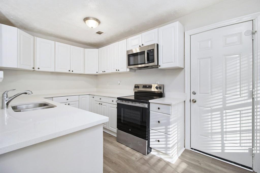 5774 Taffeta Court Lithonia, GA 30058 - Photo 7 of 25 a kitchen with stainless steel appliances granite countertop a sink a stove a microwave and cabinets