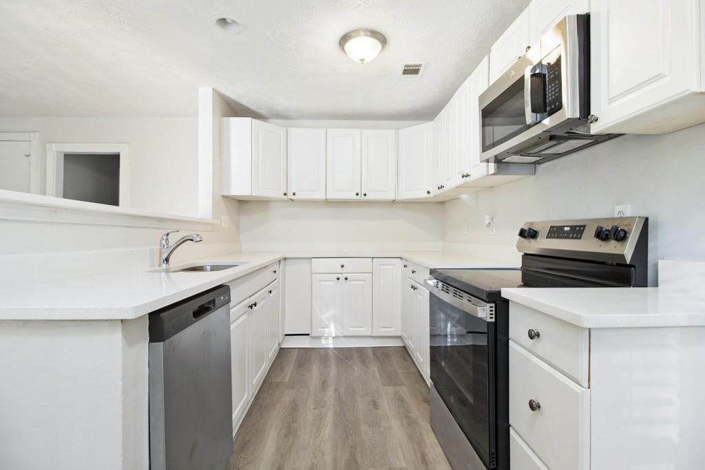 5774 Taffeta Court Lithonia, GA 30058 - Photo 9 of 25 a kitchen with stainless steel appliances a stove sink microwave and cabinets