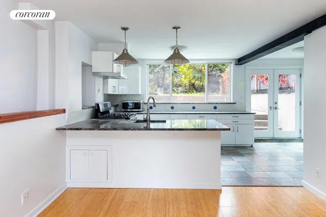 a kitchen with granite countertop white cabinets and a wooden floor