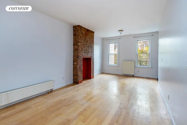 a view of an empty room with window and wooden floor