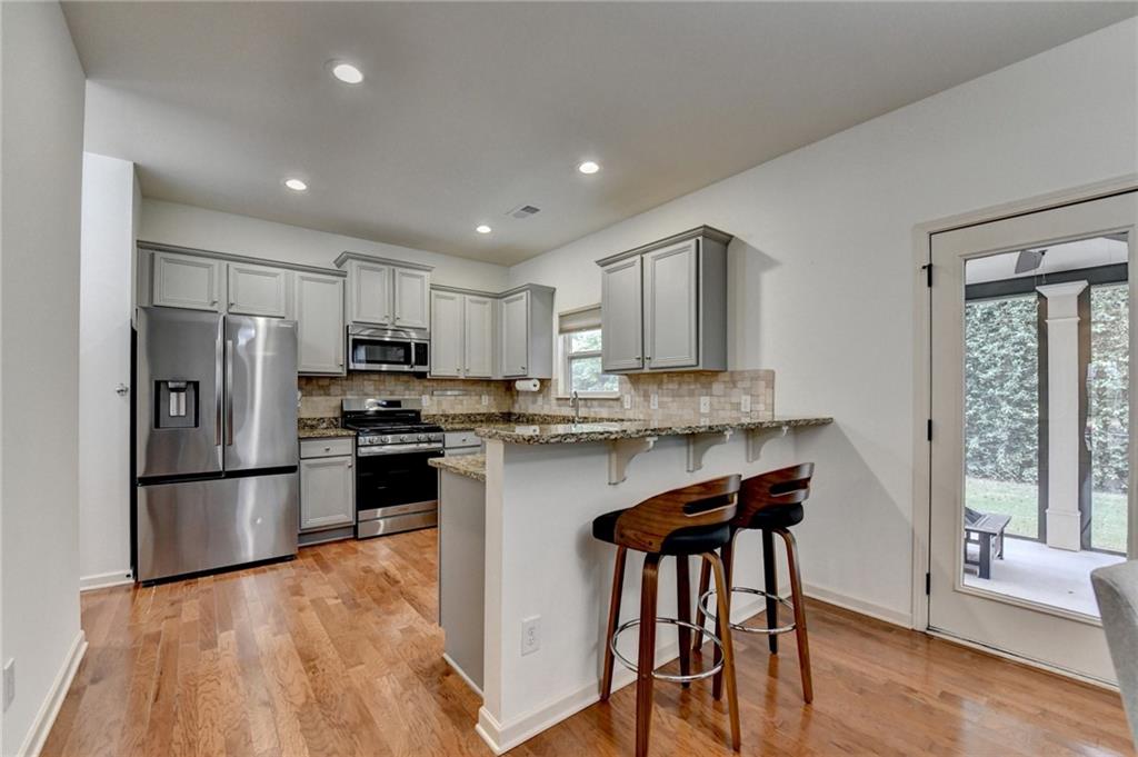5013 Groover Drive Smyrna, GA 30080 - Photo 17 of 70 a kitchen with stainless steel appliances granite countertop a refrigerator a stove a sink a dining table and chairs with wooden floor