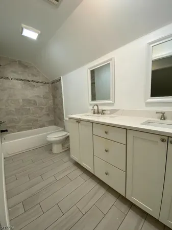 a spacious bathroom with a double vanity sink a toilet and a mirror