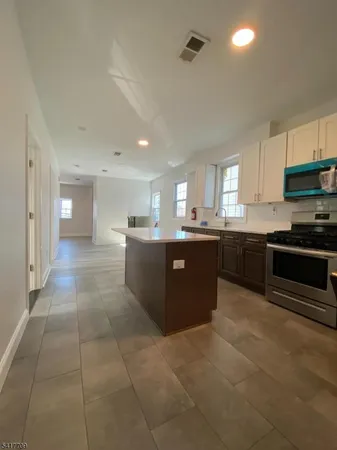 a large kitchen with stainless steel appliances granite countertop a stove top oven a sink a counter top space and cabinets