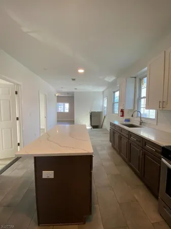 a large kitchen with stainless steel appliances granite countertop a sink and white cabinets