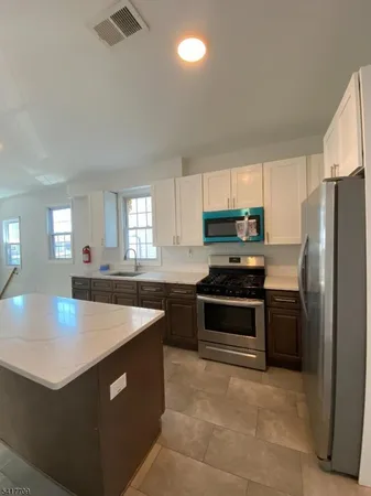 a kitchen with stainless steel appliances granite countertop a refrigerator a sink a stove a microwave and island