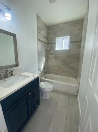 a bathroom with a granite countertop sink toilet a bathtub and a mirror