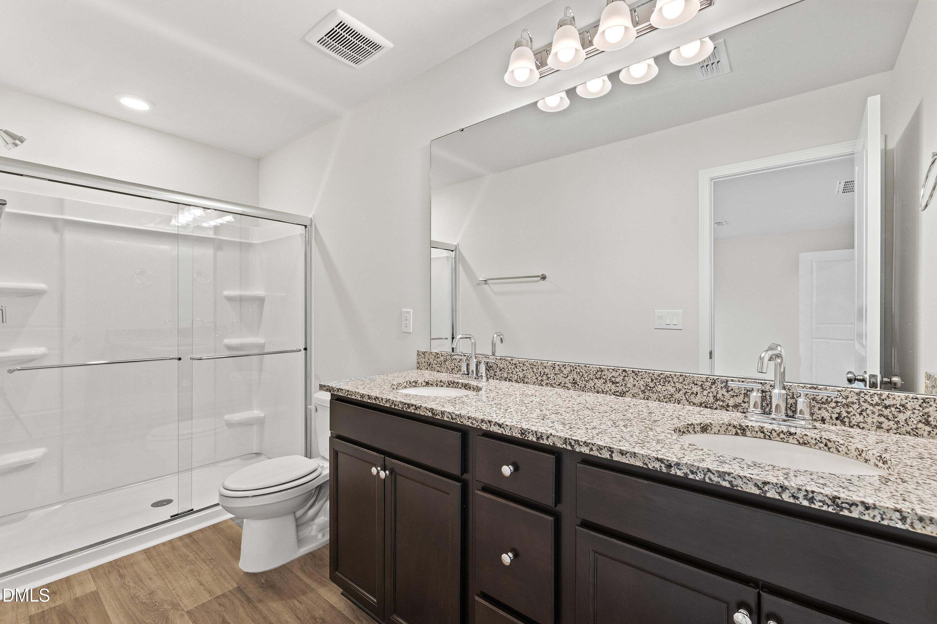 2550 Olive Chapel Road Apex, NC 27502 - Photo 30 of 41 a bathroom with a granite countertop sink a toilet a mirror and shower