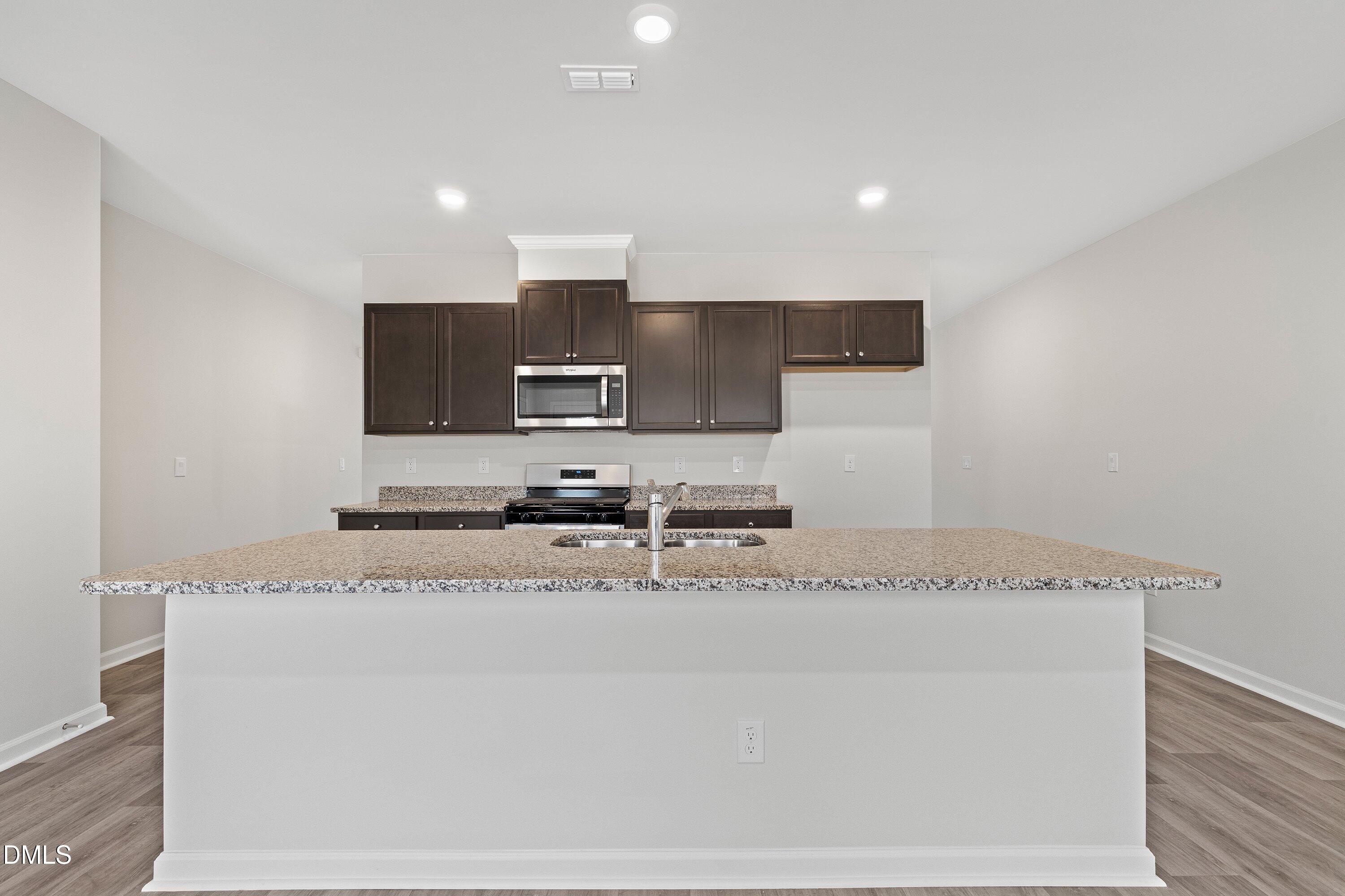 2550 Olive Chapel Road Apex, NC 27502 - Photo 10 of 41 a kitchen with granite countertop a sink a stove a microwave a counter top space and cabinets