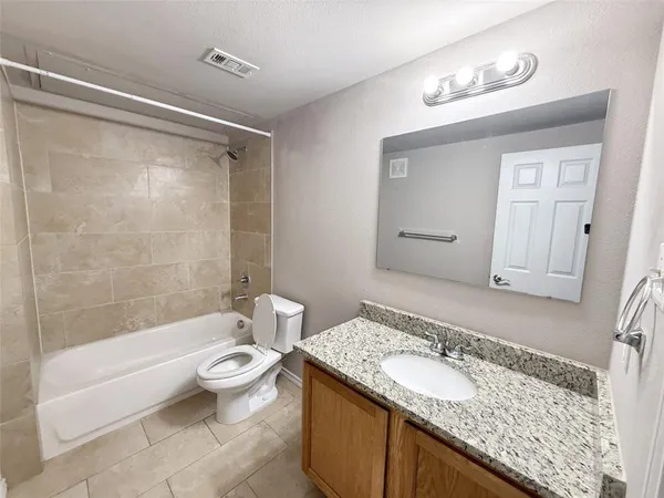 a bathroom with a granite countertop sink a toilet and shower