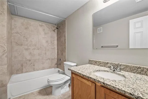 a bathroom with a granite countertop sink a toilet and shower