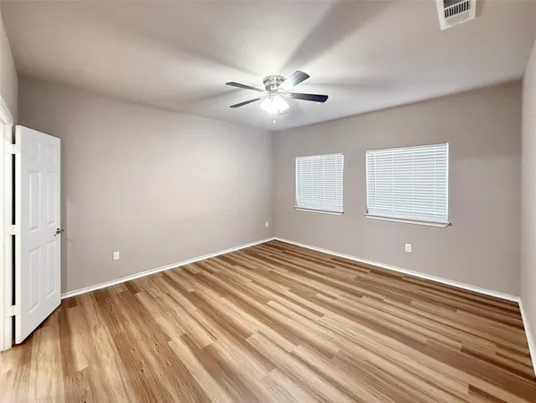 a view of an empty room with window and wooden floor