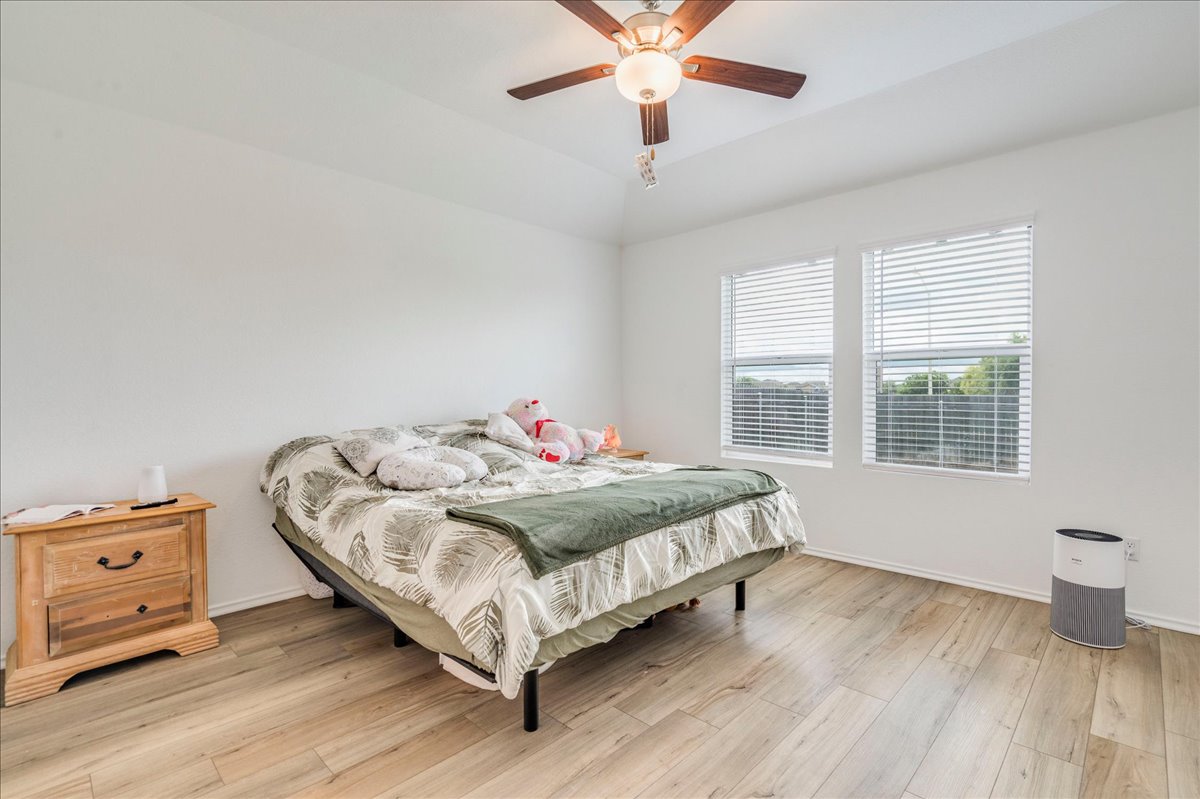 389 Salt Springs Road Kyle, TX 78640 - Photo 14 of 30 A tranquil bedroom features warm wood flooring and a recessed ceiling with a cooling fan, ideal for restful nights.