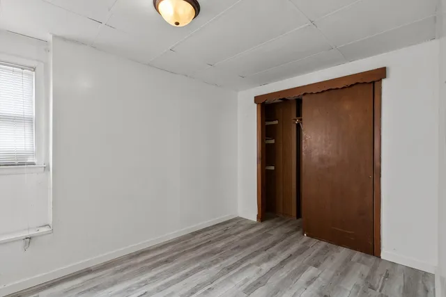 a view of an empty room with wooden floor and window