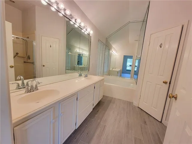 a spacious bathroom with a double vanity sink a mirror and a shower