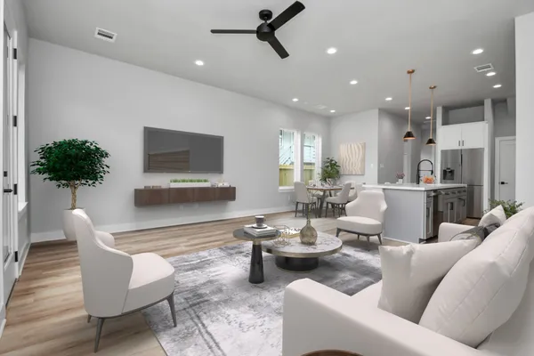 a living room with lots of furniture kitchen view and a potted plant