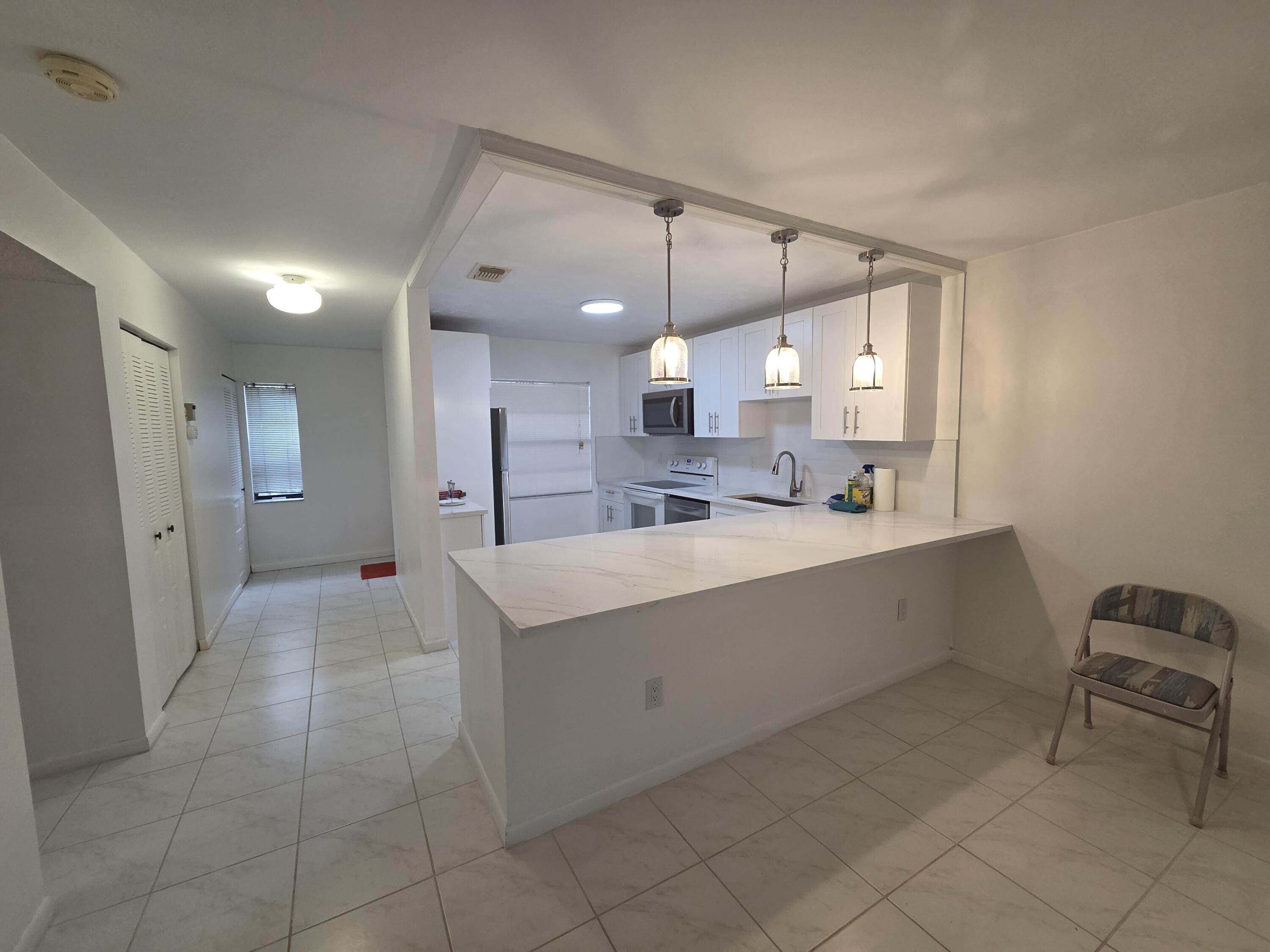 a large white kitchen with a sink stainless steel appliances and cabinets